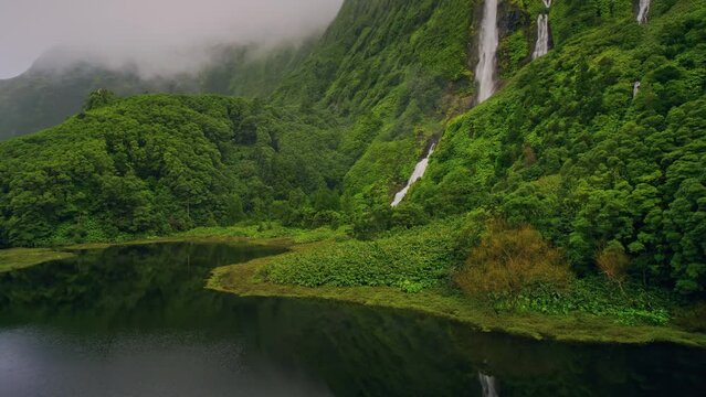 green mountains with waterfalls of Poco Ribeira do Ferreiro, Alagoinha, Flores Island, Azores, Portugal, Europe. Aerial view of amazing natural landscape with cliffs, 4k footage