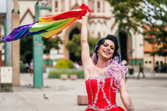 Homosexual dressed as a woman raising the gay flag.