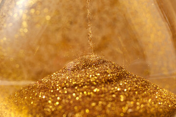 Golden sand pouring inside vintage hourglass