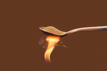 Spoon of golden sand over fire flame