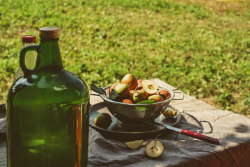 A large bottle of fruit cider on rustic table with harvest of pears, on an autumn day
