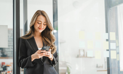 Charming brunette Asian business woman using mobile phone, Pretty Asian lady massaging in cellphone at modern office.