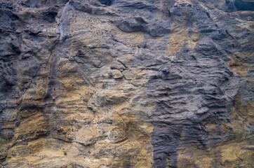 Textured Stratified Lava Wall in Tones of Gray, Black and Tan for an Environmental Background.