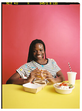 Smiling woman with sald and burger in studio