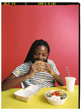 Smiling woman with sald and burger in studio