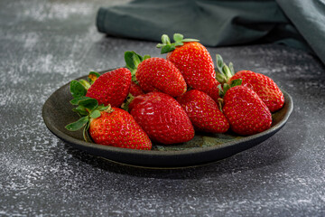 red fresh and delicious strawberries on a dark plate. dark food photography