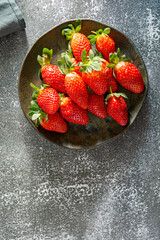 red fresh and delicious strawberries on a dark plate. dark food photography