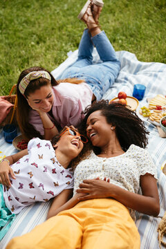 Multiethnic lesbian couple with their daughter enjoying picnic