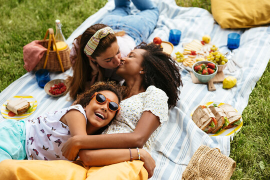 Multiethnic lesbian couple with their daughter enjoying picnic
