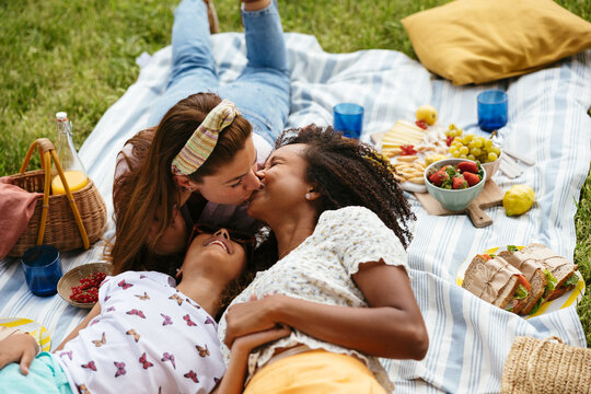 Multiethnic lesbian couple with their daughter enjoying picnic
