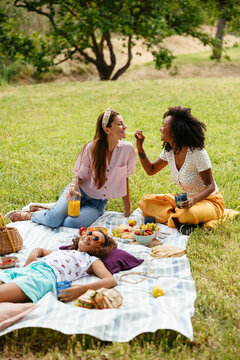 Multiethnic lesbian couple with their daughter enjoying picnic