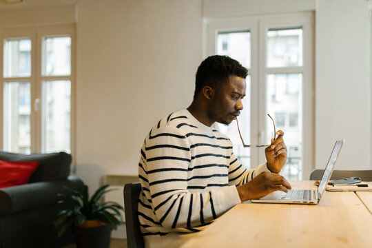 Millennial black man typing on a laptop indoors