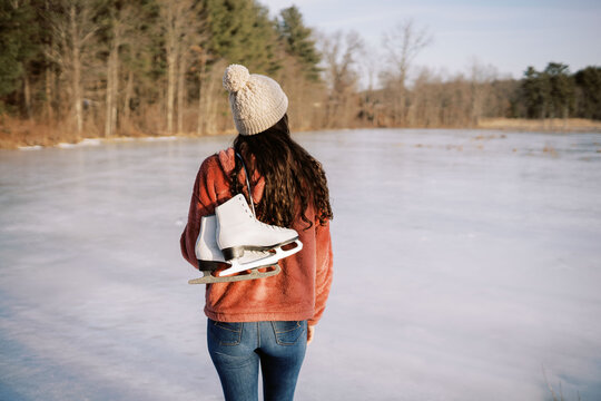 young woman by lake holding skates