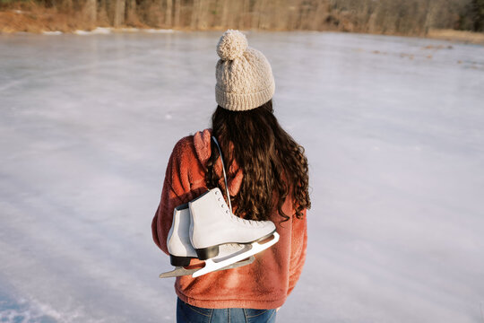 young woman by lake holding skates