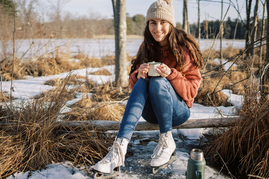 woman with ice skates smiling with  on a hot drink