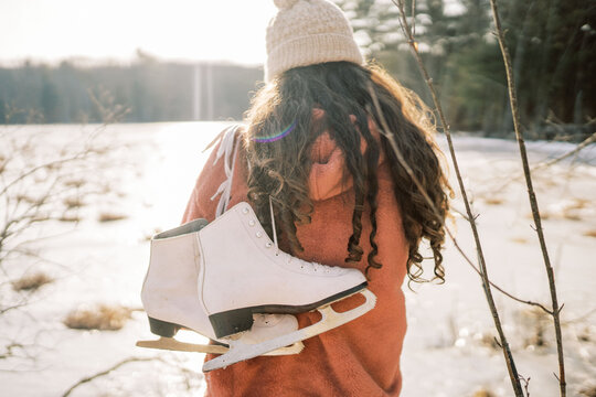 young woman by lake holding skates
