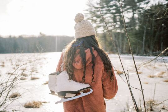 young woman by lake holding skates