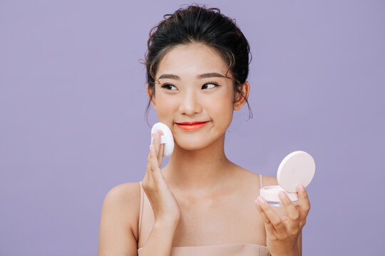 Beautiful young woman applying face powder with puff applicator