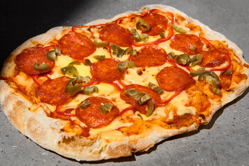 Traditional italian food - Pizza pepperoni on dark background. Pepperoni pinsa on gray stone table...
