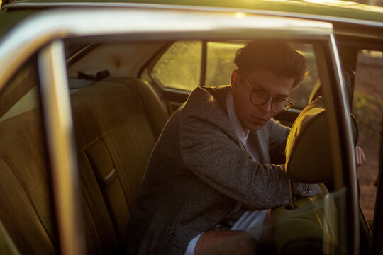 A stylish man inside a car with  sunlights