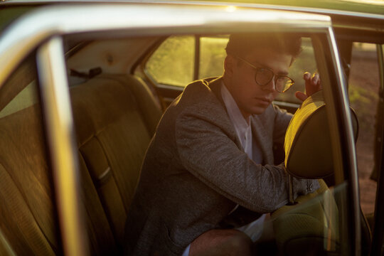 A stylish man inside a car with  sunlights