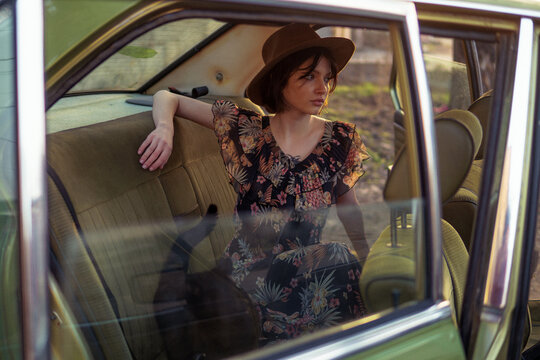 Stylish Woman with a hat and black cat sitting in the old car