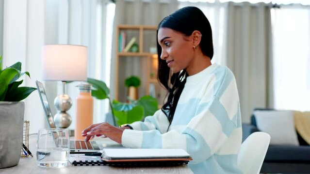 Female student typing and completing an assignment for college on a laptop at home. One Indian girl communicating with a lecturer through email and finishing her schoolwork in the living room