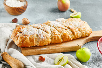 Sweet pie with dried fruit on wooden board. Composition with fruit secs on concrete background with textile and spices. Homemade pie with dried fruit in rustic style on gray table.