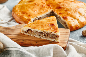 Sweet pie with apple, nuts and raisin on wooden board. Composition with apple pie on concrete background with textile. Homemade pie with dried fruit and nuts in rustic style on gray table.