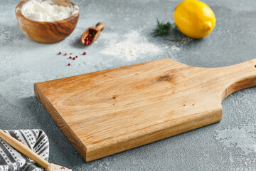 Food mockup. Empty wooden board on concrete table with cooking  ingredients. Wooden board  with spices, greens and tomatoes for menu. Food menu mockup. Cooking composition with empty place.