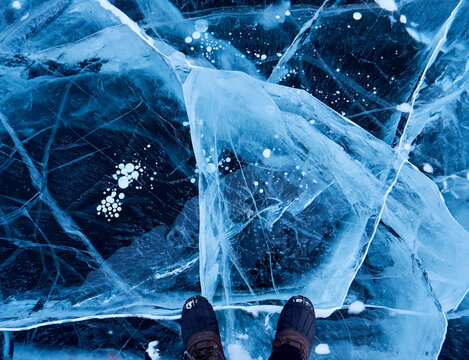 Shoes stand on beautiful exotic blue cracked frozen sea ice surface