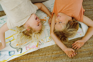 Two cheerful brothers lie on the floor after drawing 