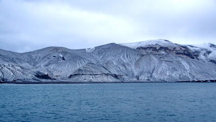 Snow dusted mountains surrounding a crater bay on Deception Island, Antarctica