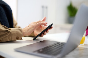 Pensioner browsing mobile at workplace at home.