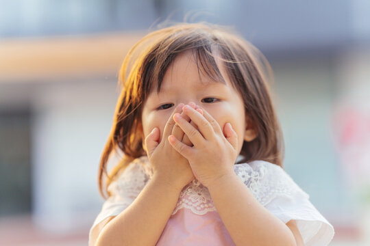 little girl covering nose with hands