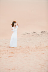 Fototapeta na wymiar Portraits of woman with white dress walking on a bright summer day, in the Mui Ne desert Vietnam holliday vacation concept.