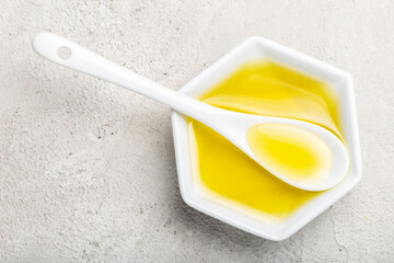 castor oil in spoon and white container, top view