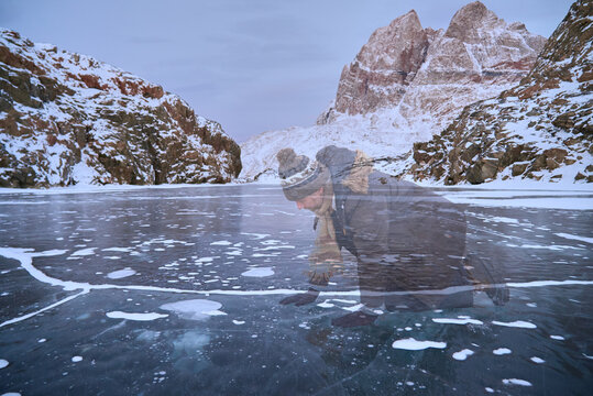 Arctic winter, person half dissolved atop frozen sea ice surface crack