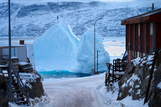 Enormous iceberg floats past town house, island settlement, Greenland