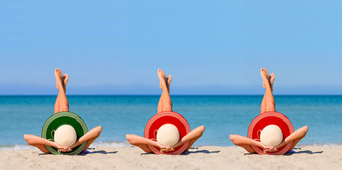 Three young girls on the beach wearing straw hats in the colors of the flag of Portugal. The concept of the perfect holiday in the resorts of the Portugal. Focus on hats.