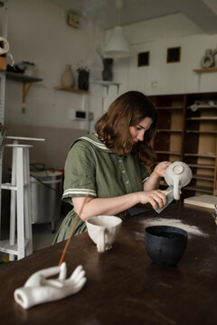 Young artist using sponge to peel clay product from surplus