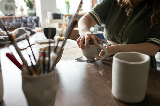 Young craftwoman using sandpaper to scrub the mug
