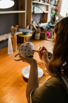 A young woman draws circles on a mug