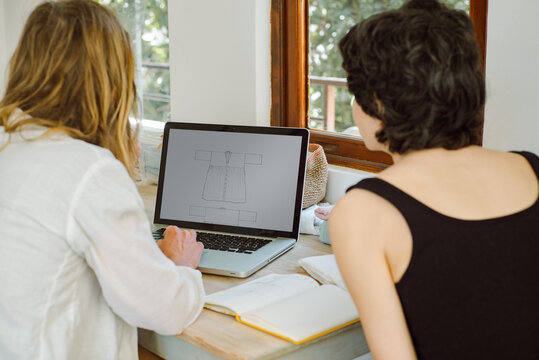 Two young women discussing dress design