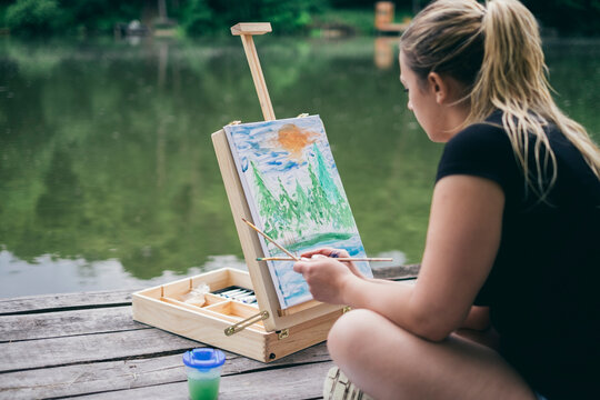 woman practicing painting at a forest lake