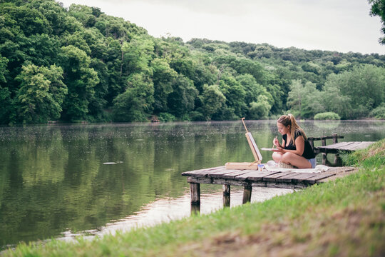 woman practicing painting at a forest lake