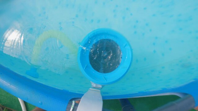 Close-up of the camera being lifted from the pool cleaning skinner to the surface. Water droplets fall into the pool. Top view. Concept of cleaning the pool at home