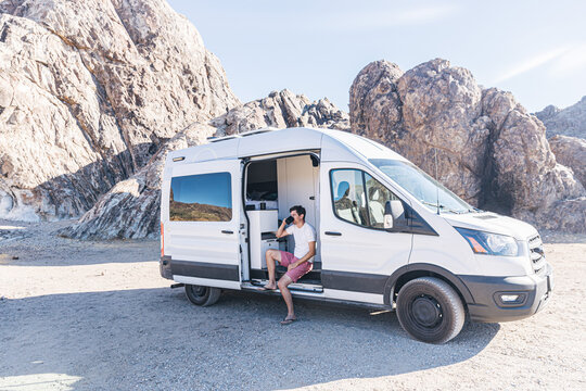 Man drinking coffee sitting in a camper van