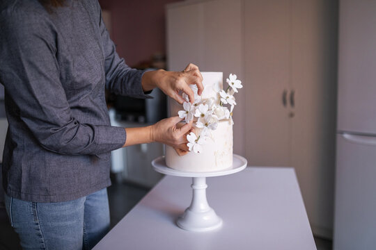 anonymous female pastry chef decorating a two-tier cake