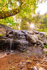 Naklejka na ściany i meble Waterfall in wilderness area of Australia with sun rays in background. 